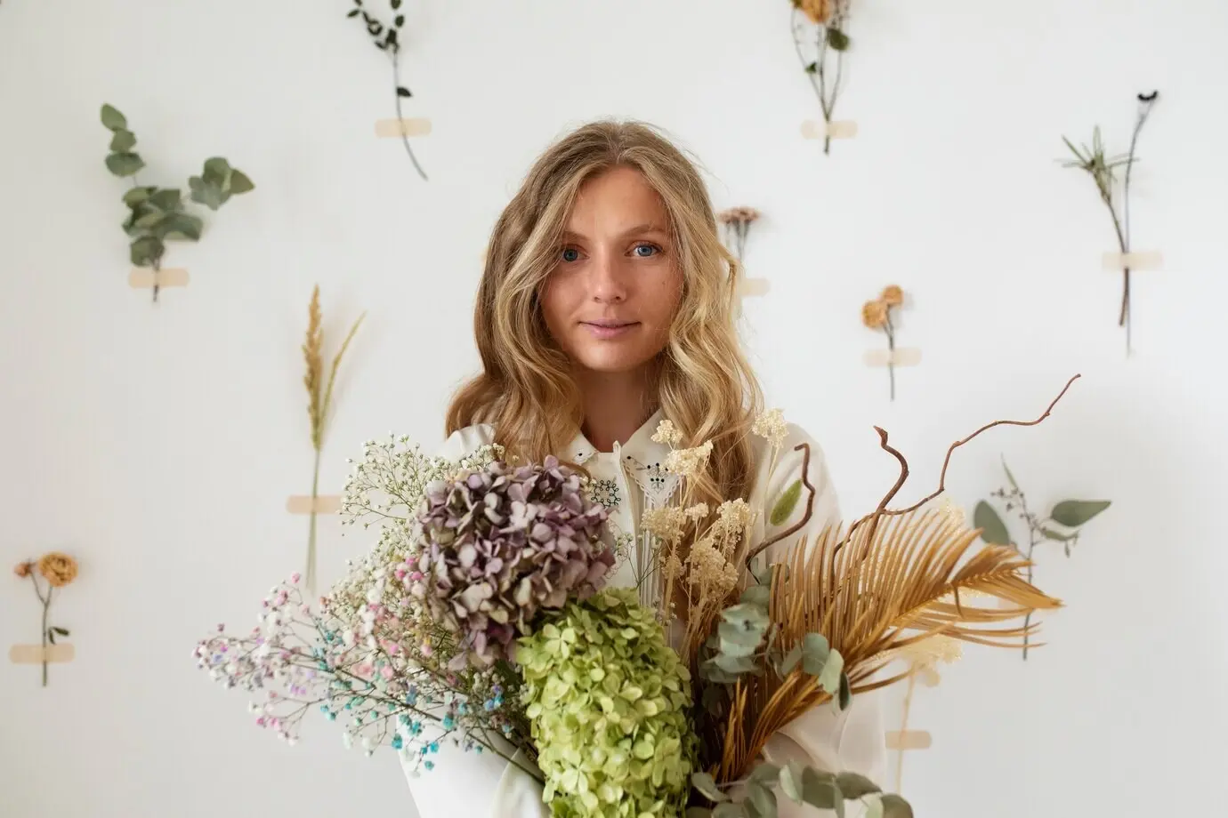 A woman holding dried flowers, seen from the front.