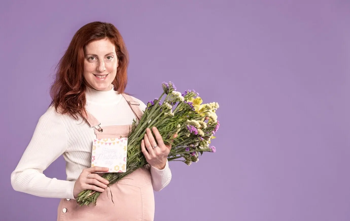 Smiling pregnant woman holding a bouquet of flowers